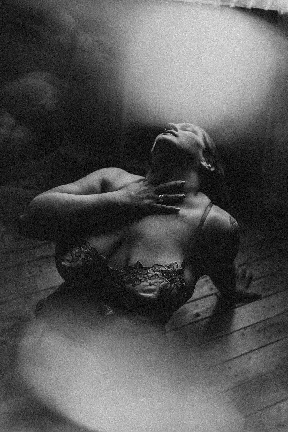 Dramatic black and white intimate portrait with lace details on hardwood floor.