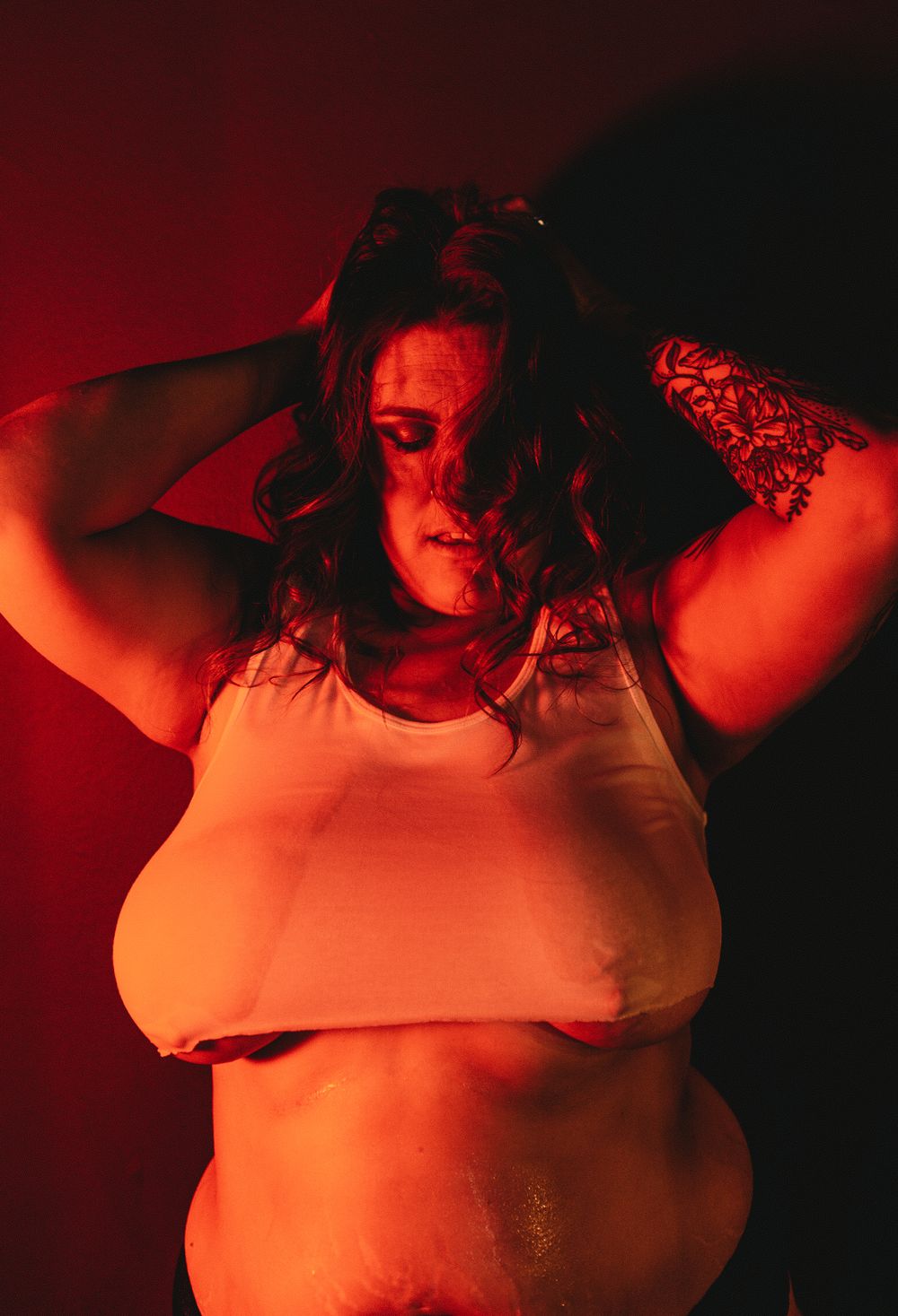 Dramatic self-expression portrait with red lighting and white tank top.