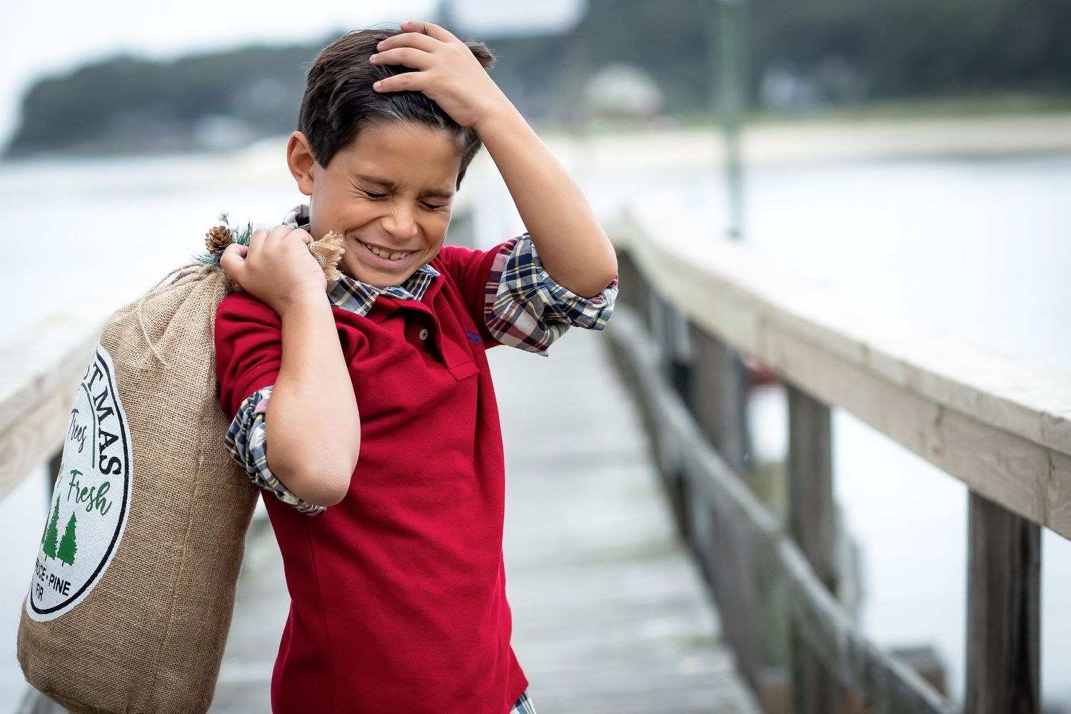 Candid photo of someone laughing on a wooden pier while holding their head.