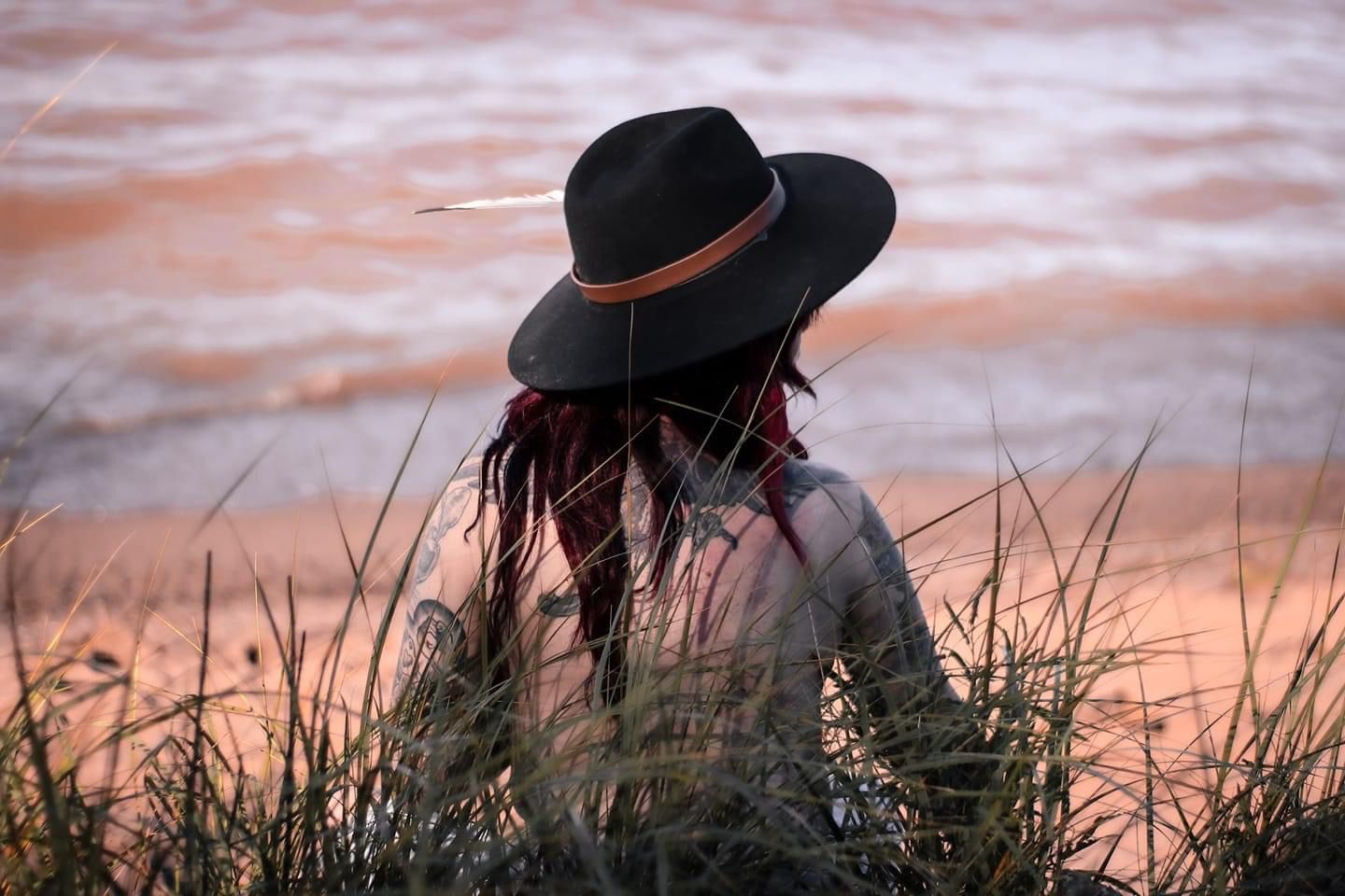 Shirtless tattooed woman wearing a hat posing in nature in Minnesota