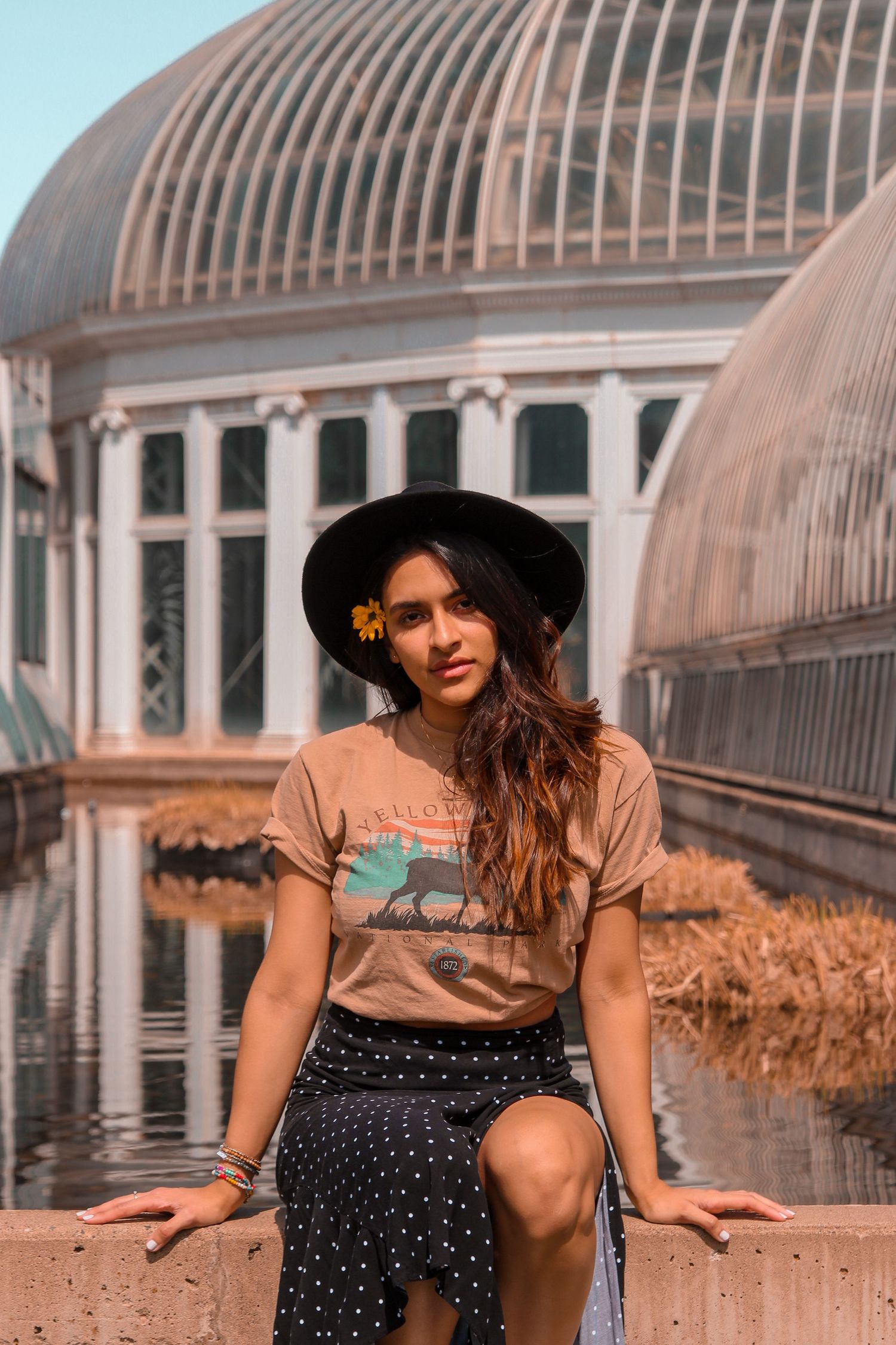 woman wearing 90's fashion posing in front of a massive greenhouse como zoo st.paul