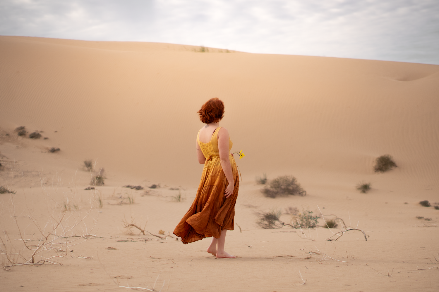 Woman posing in the imperial sand dunes in California wearing a bright dress
