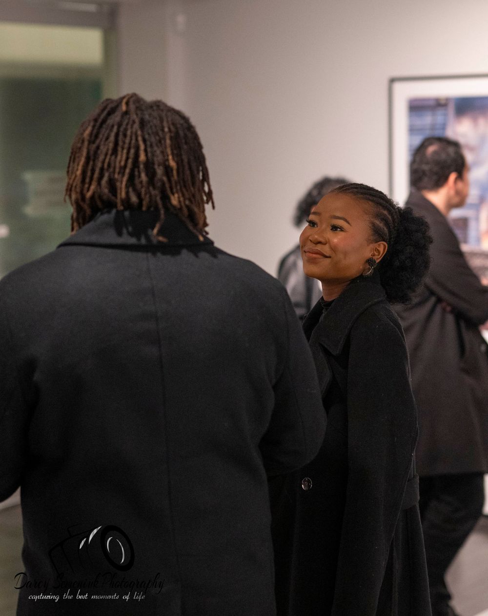 A series of dark silhouettes of people with dreadlocks standing in a dimly lit hallway.