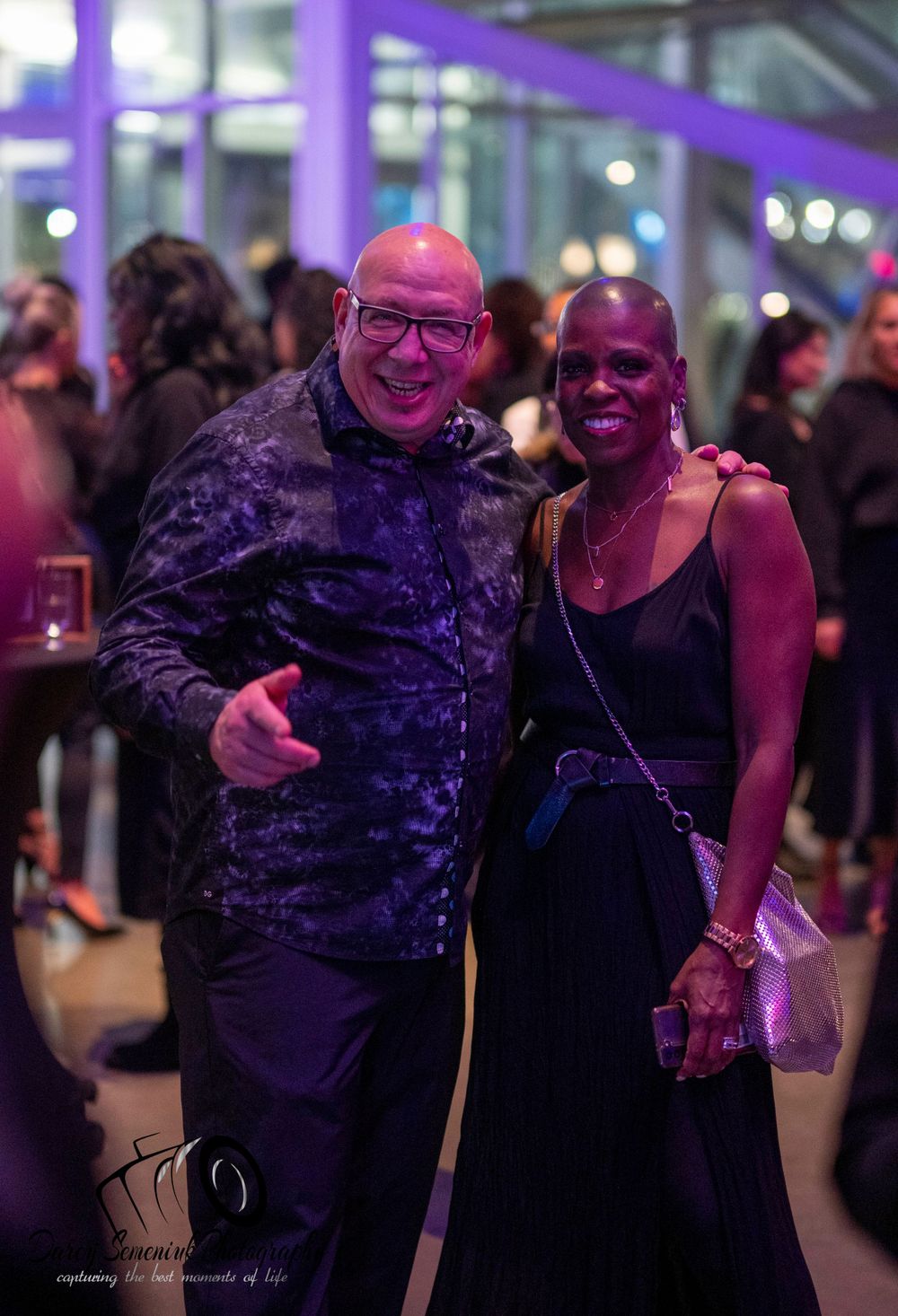 Two people dancing together in a dimly lit venue with purple lighting and joyful expressions.