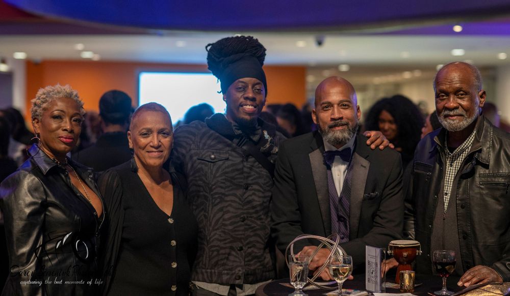 A group of people gather together at an indoor event wearing formal attire and smiling for photos.