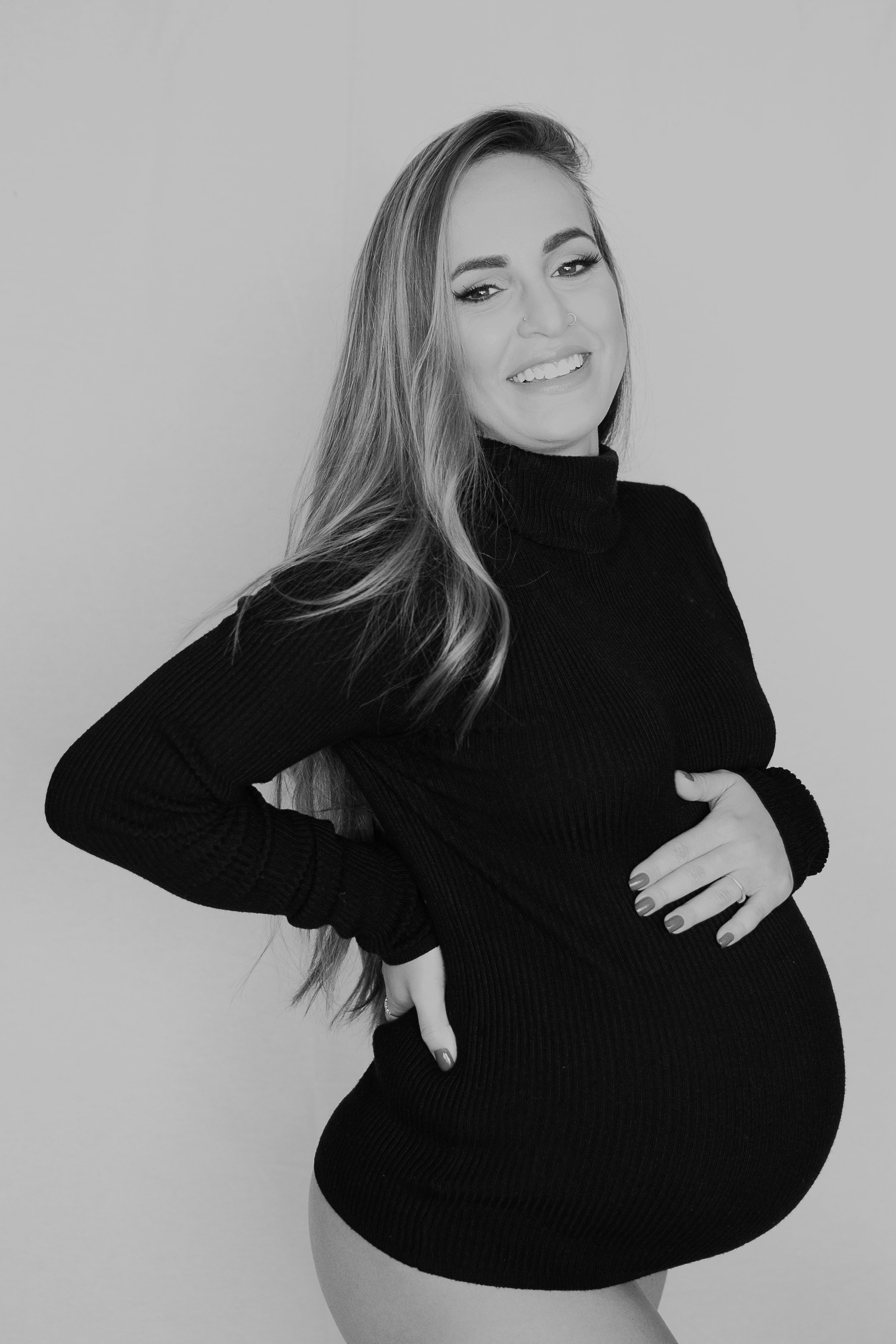 Black and white portrait of expectant mother in ribbed turtleneck sweater.