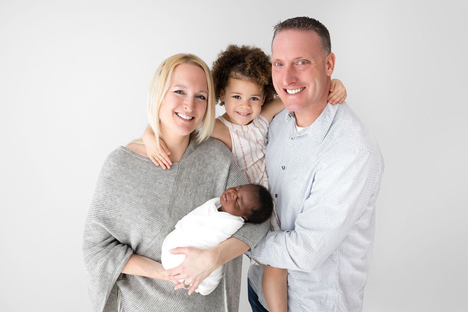 Family of four holding newborn baby boy. Photo taken by Santa Fe newborn photographer Blooming Desert Photography.