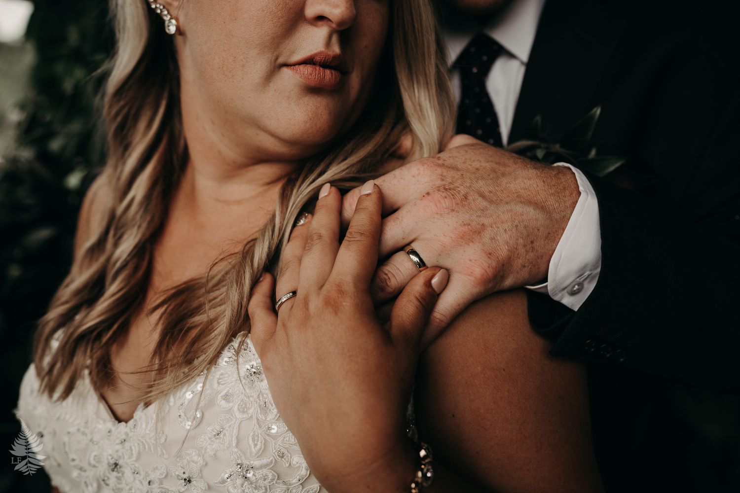 bride holding grooms hand on her shoulder