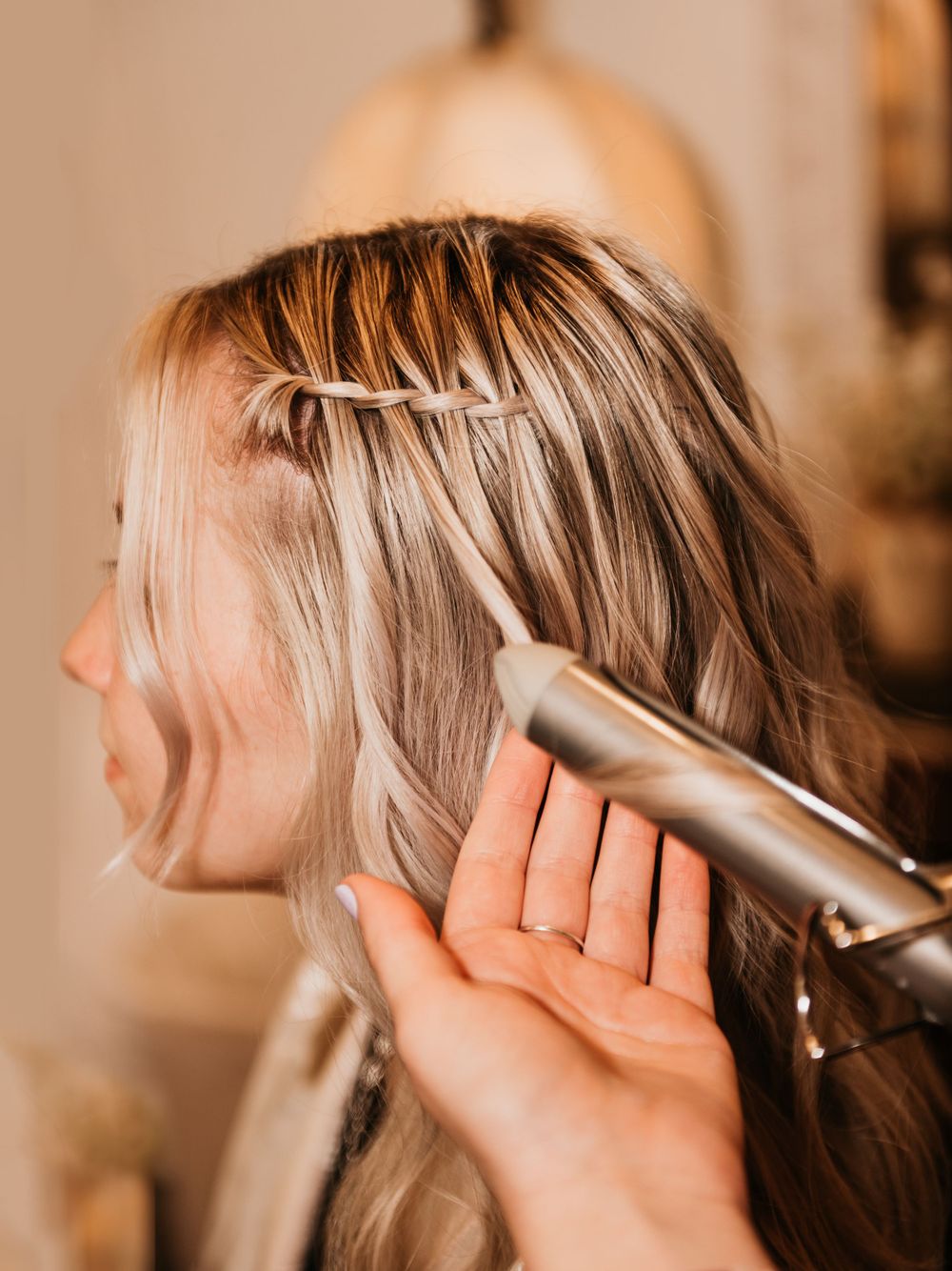 Hair styling in progress with curling iron on blonde hair.