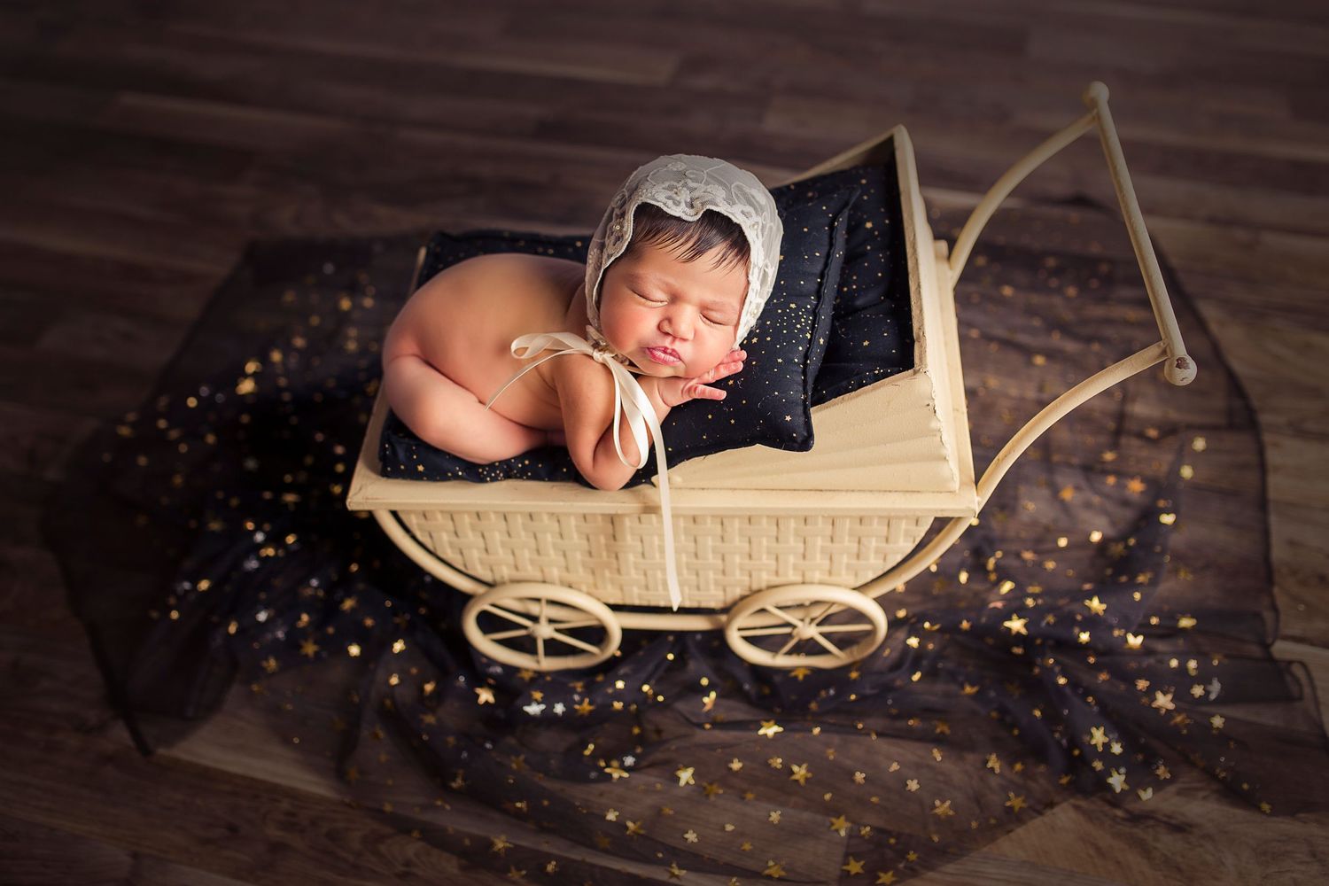 bebe recien nacida con gorrito blanco posada dentro de un coche antiguo decoracion de estrellas