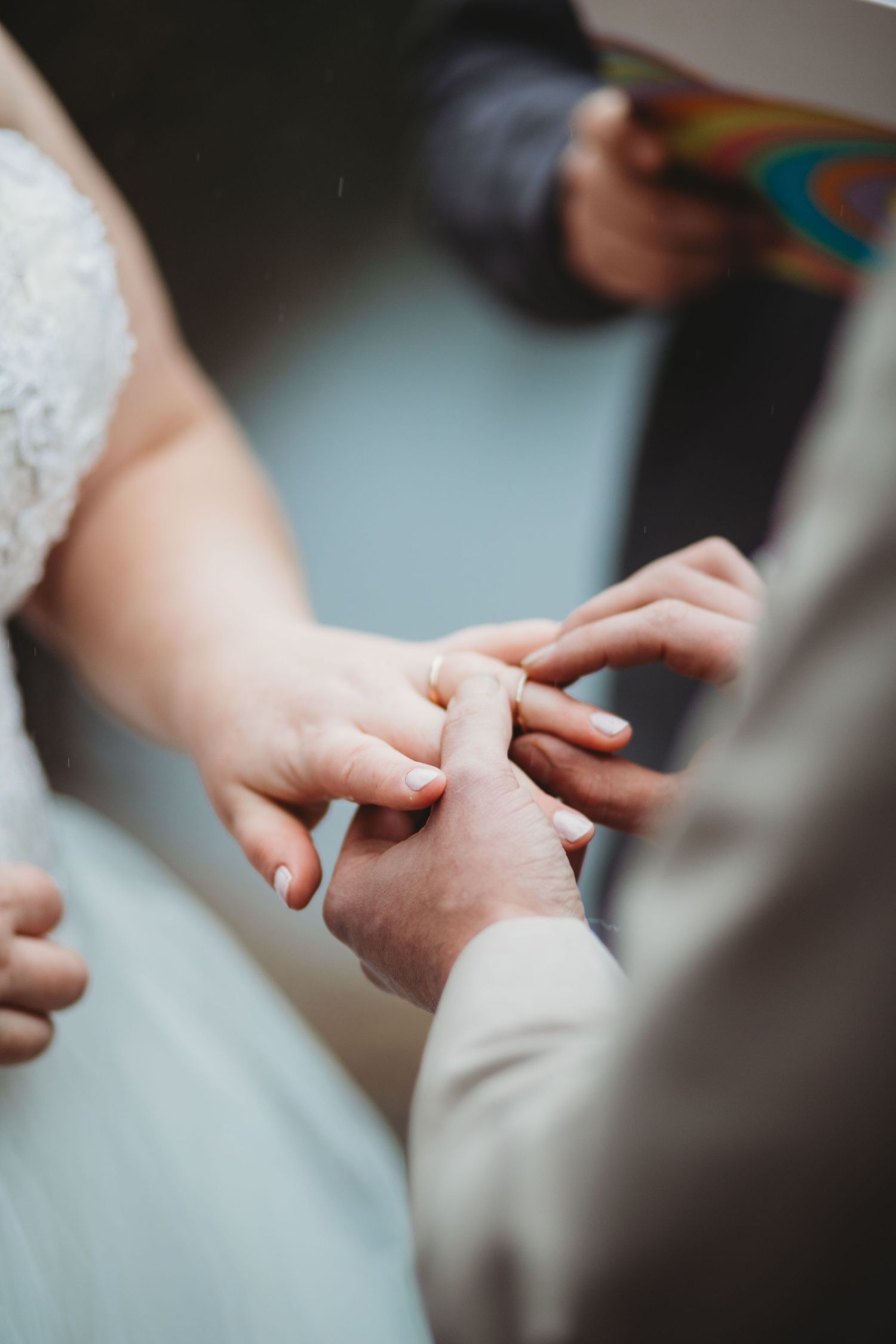 A close up image of a groom putting a ring on his bride as they say their vows.
