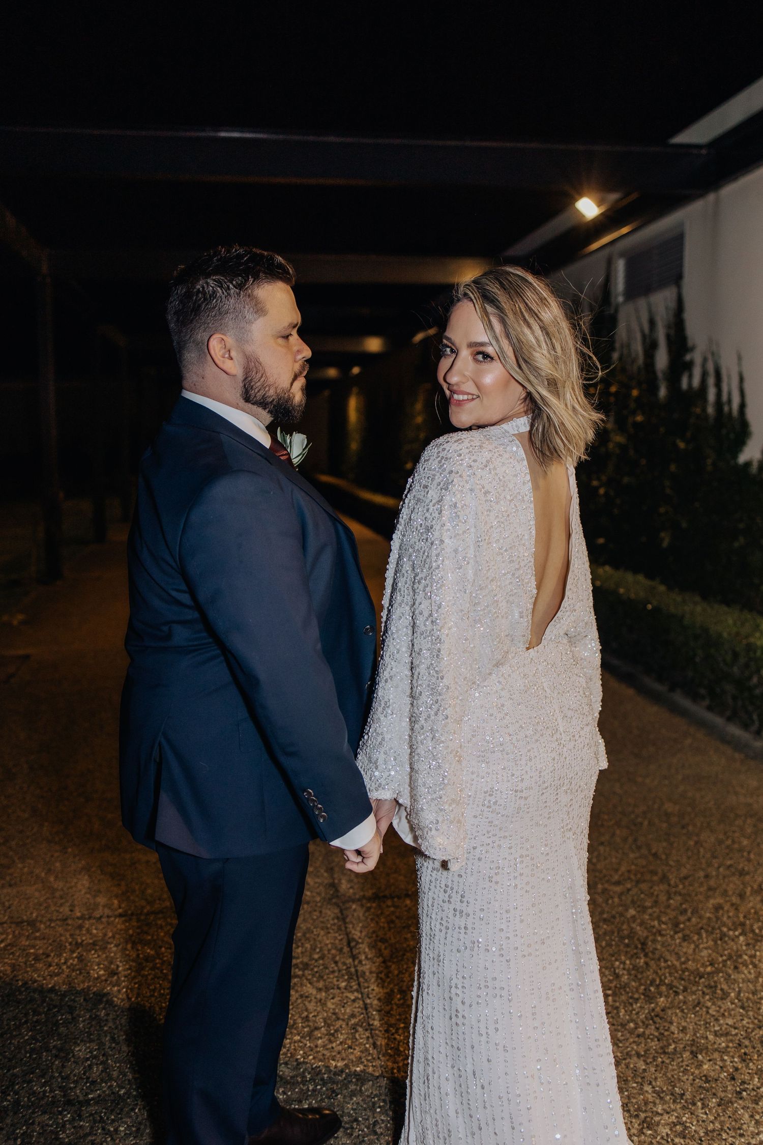 Couple shares romantic evening moment outside venue in formal wedding attire.