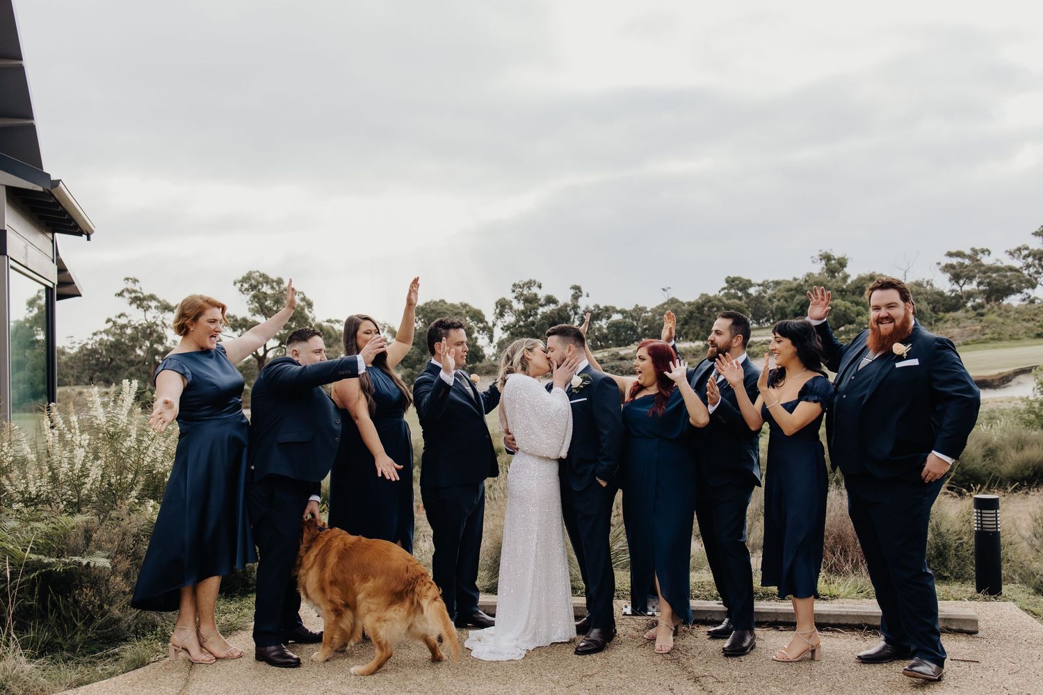 Wedding party group shot with guests lined up outdoors.