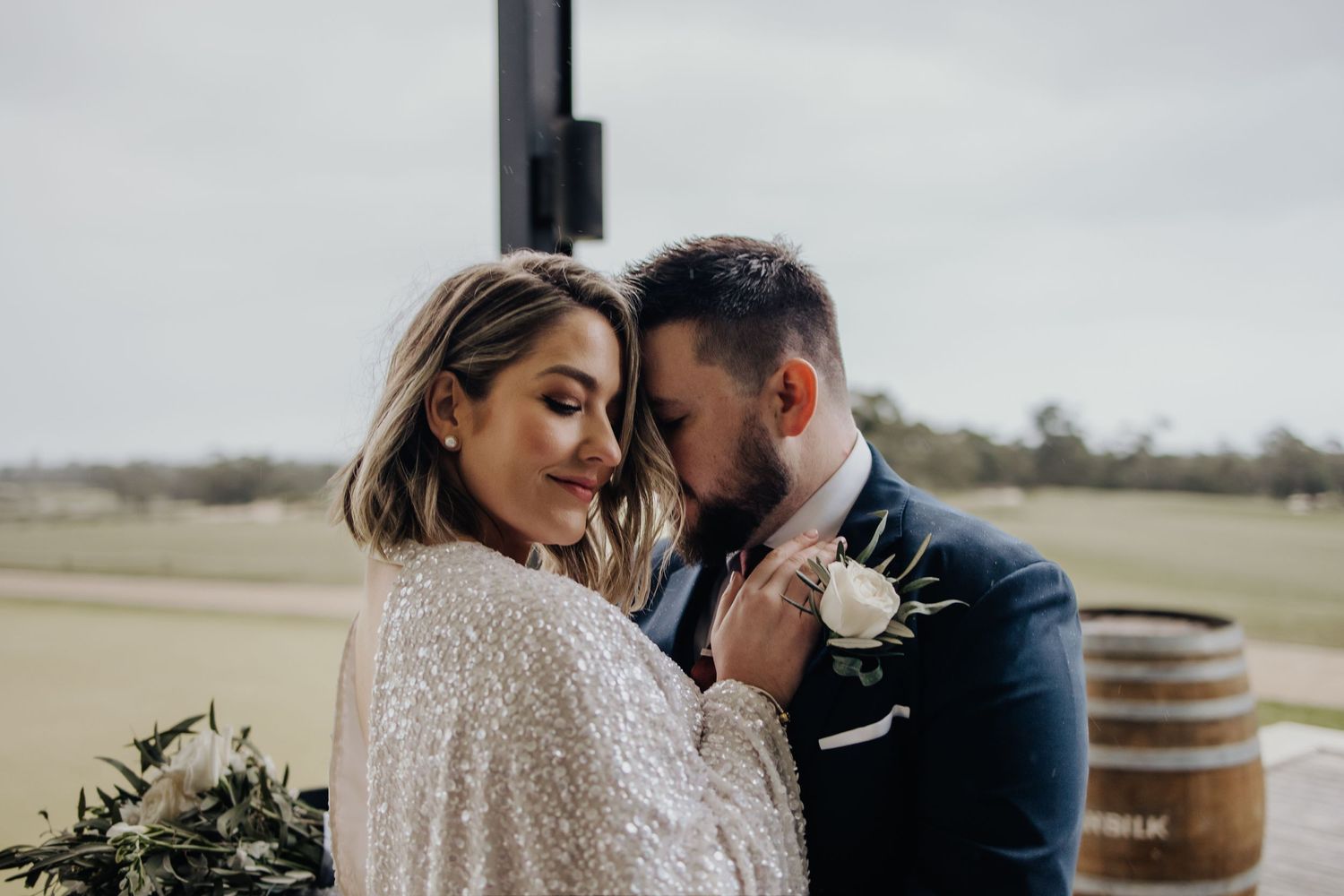 Romantic wedding couple shares intimate moment in elegant attire outdoors.