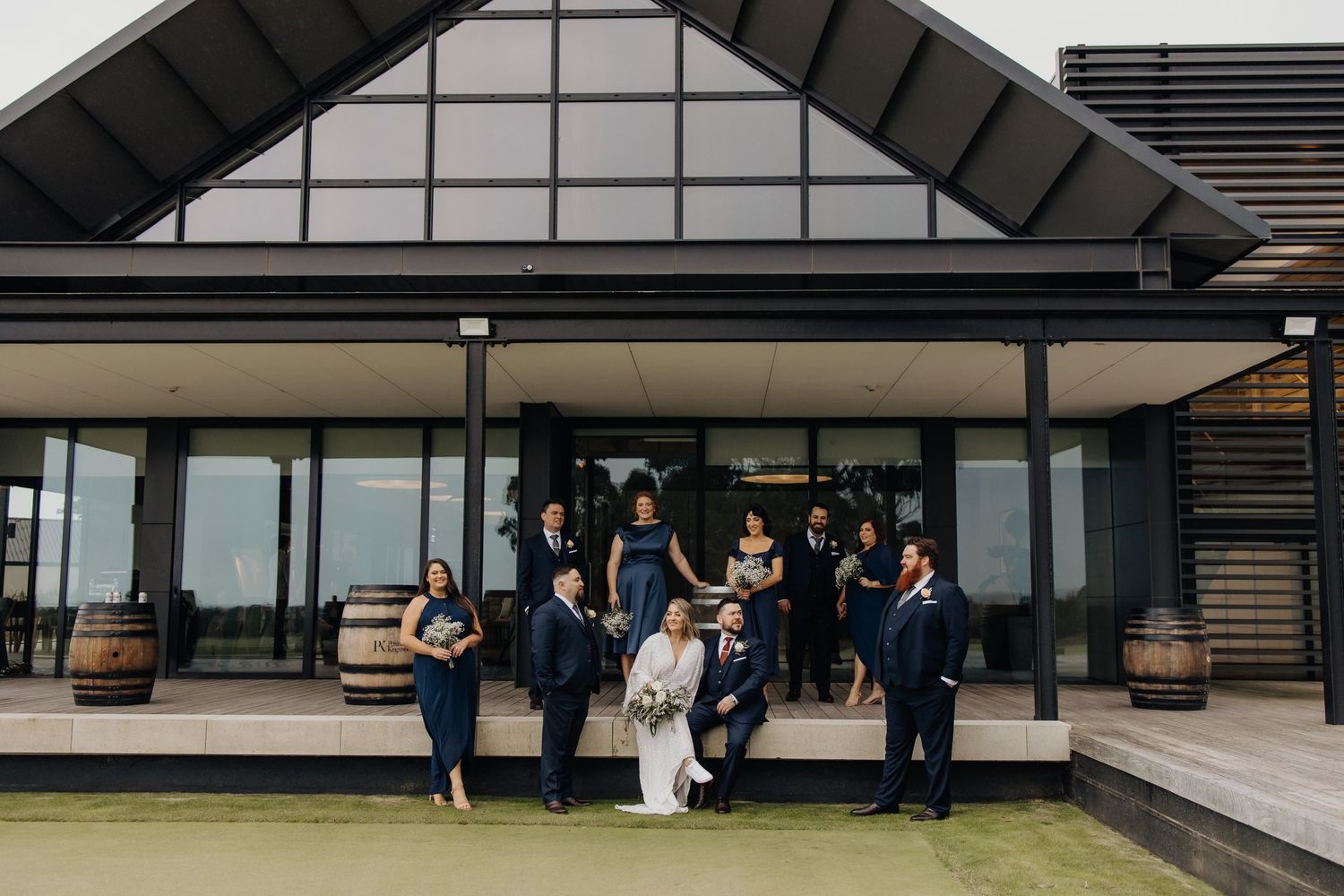 Modern architectural building with glass windows serves as backdrop for wedding photos.