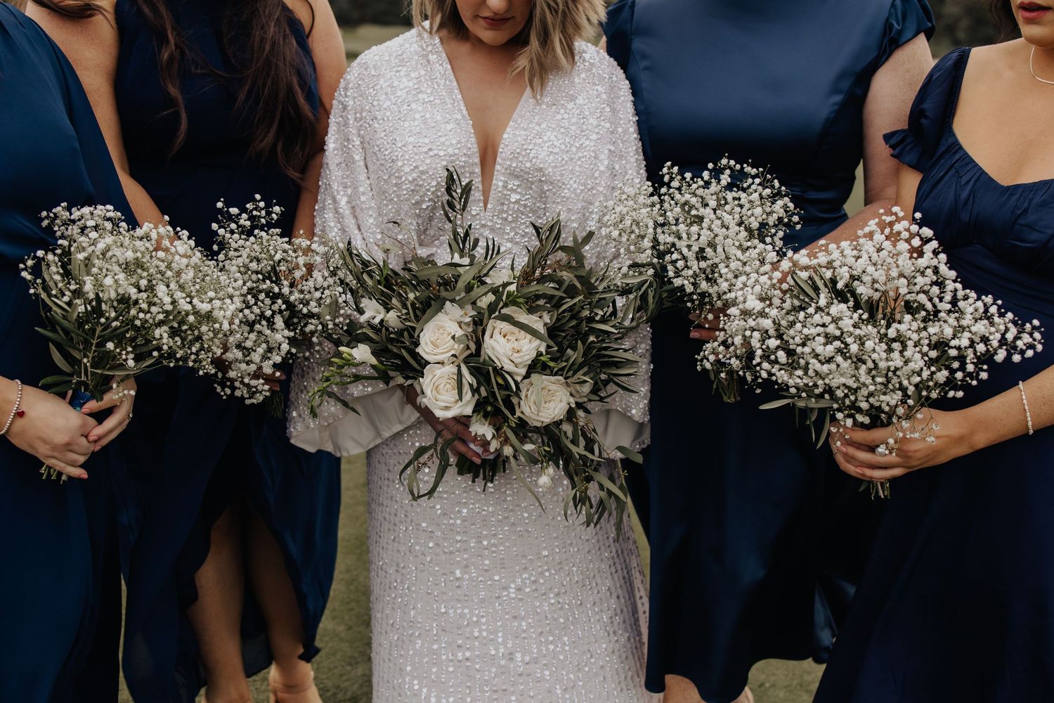 Close-up of wedding party holding delicate white and purple floral bouquets.