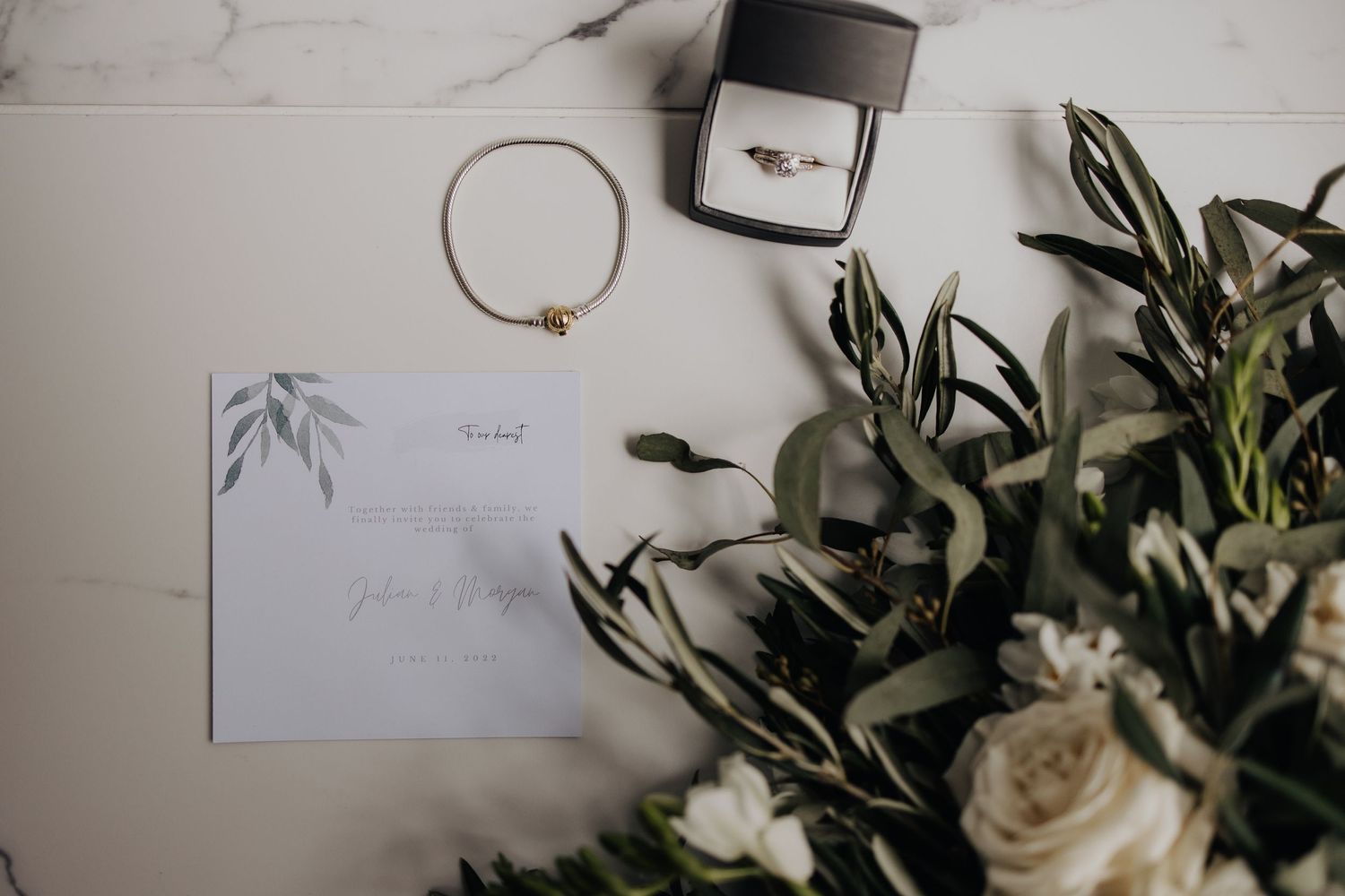 Wedding details including floral arrangements and stationery styled on white surface.