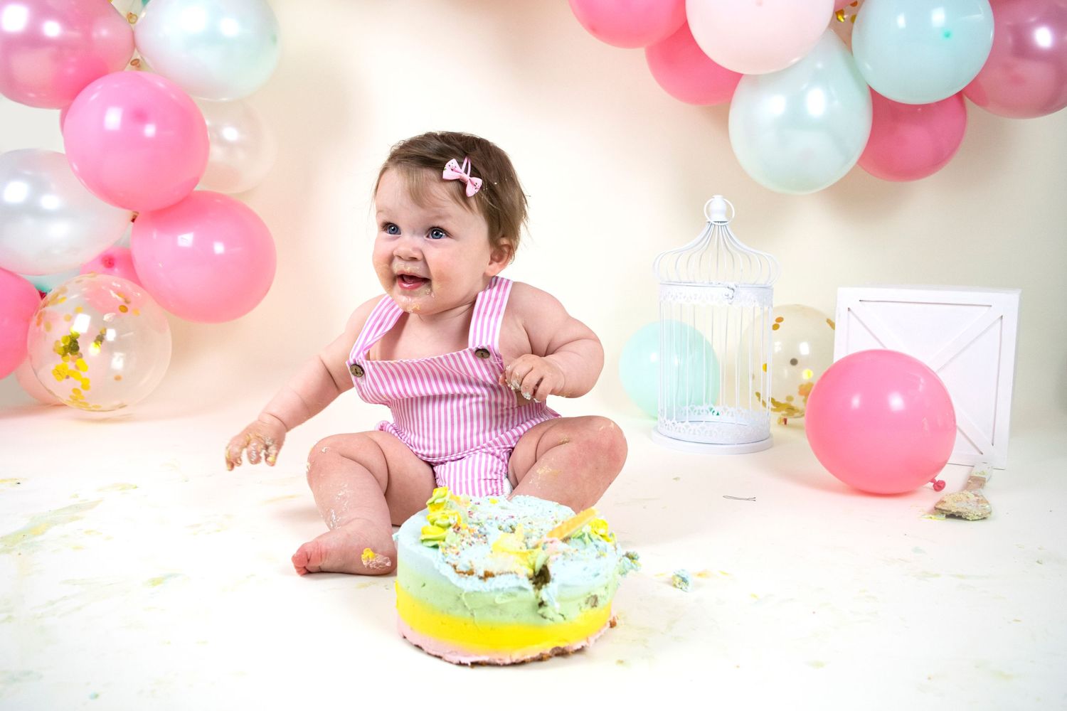 one year old little girl in pink romper for first birthday cake smash session taken by heather katie photography