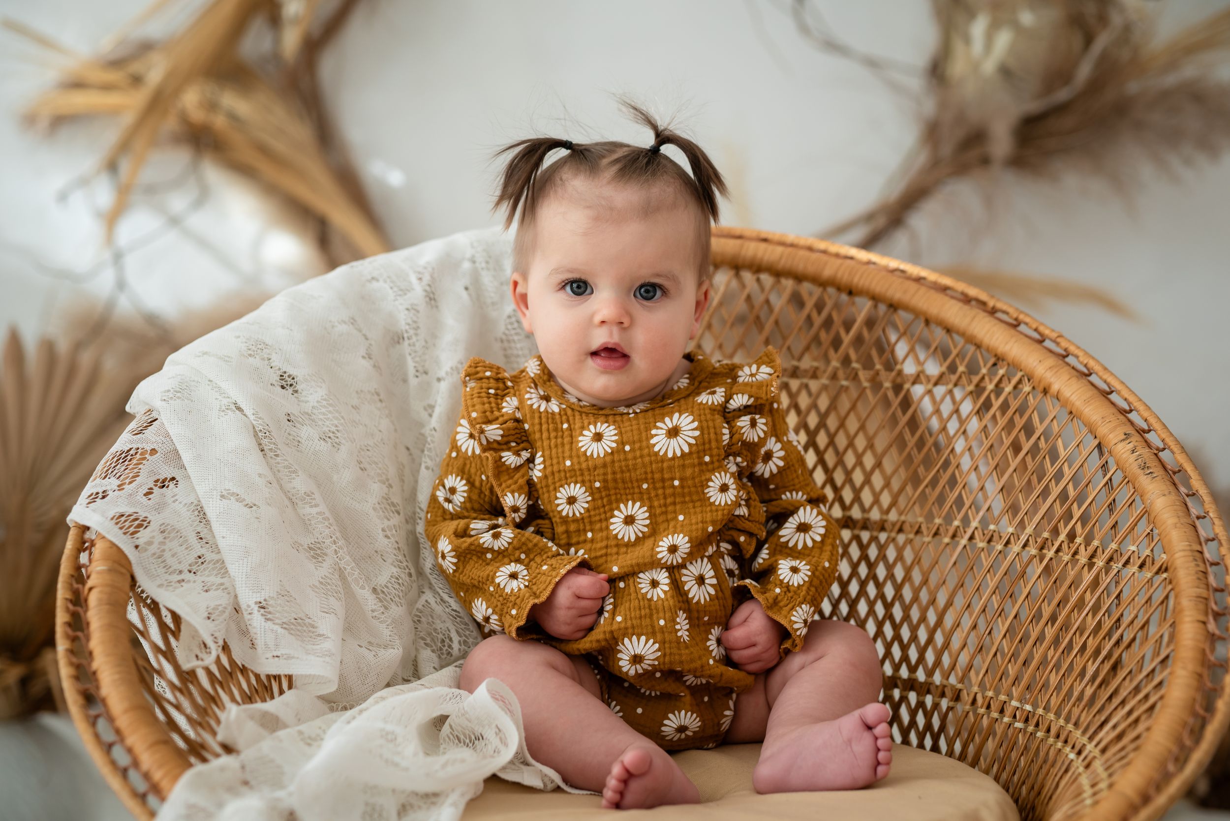 Baby girl sitting on wicker chair facing the camera