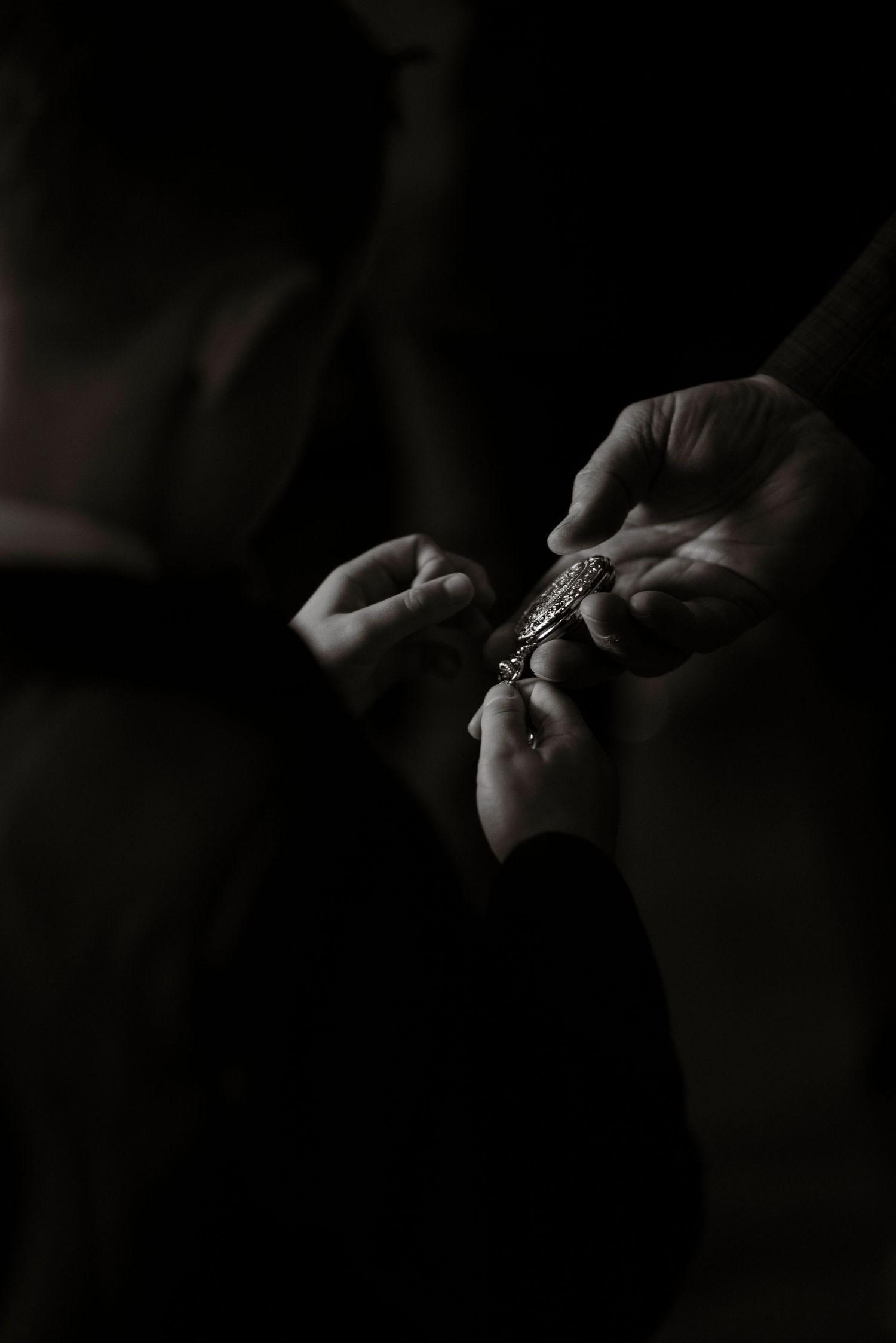 Black and white images of a son holding a pocket watch in his fathers hands