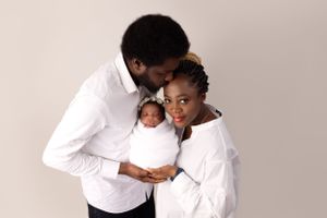 Studio portrait of family in matching white outfits against neutral background.