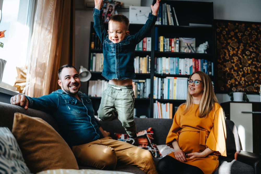Family relaxing in cozy living room with bookshelves and natural lighting.