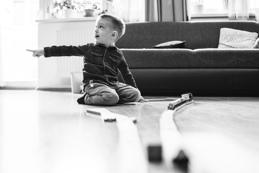 Young child playing with toys while sitting on the floor near a sofa.