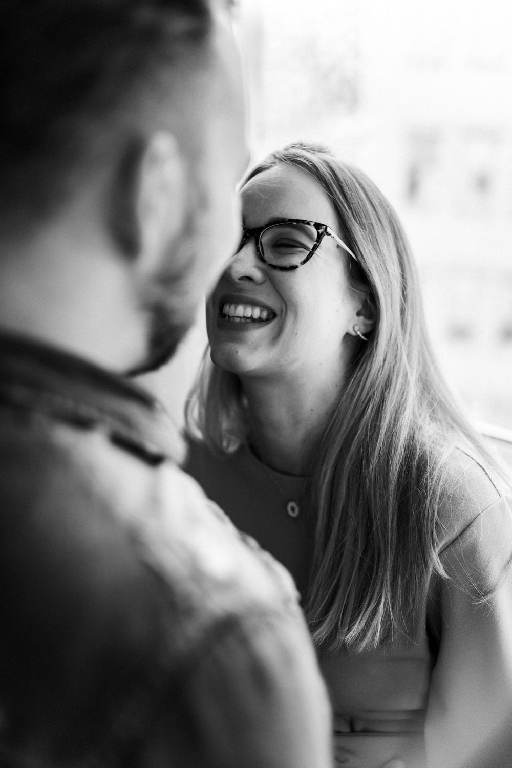 A candid black and white photo captures laughter between a couple.