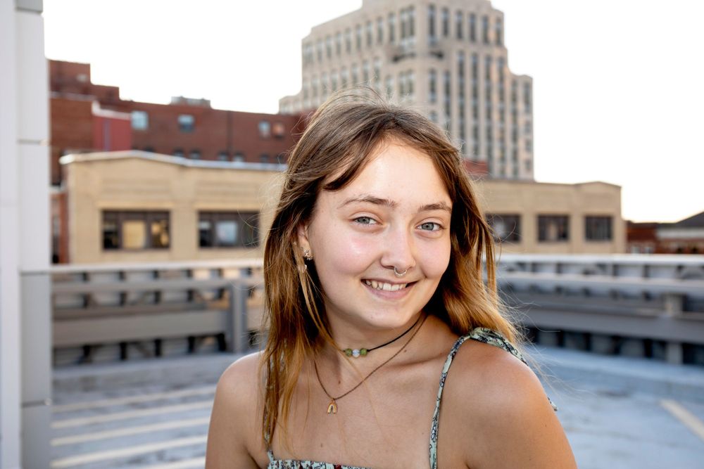 Rooftop portrait with city buildings and bright natural lighting.