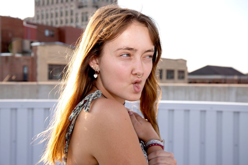 Portrait with flowing hair against urban rooftop background at golden hour.