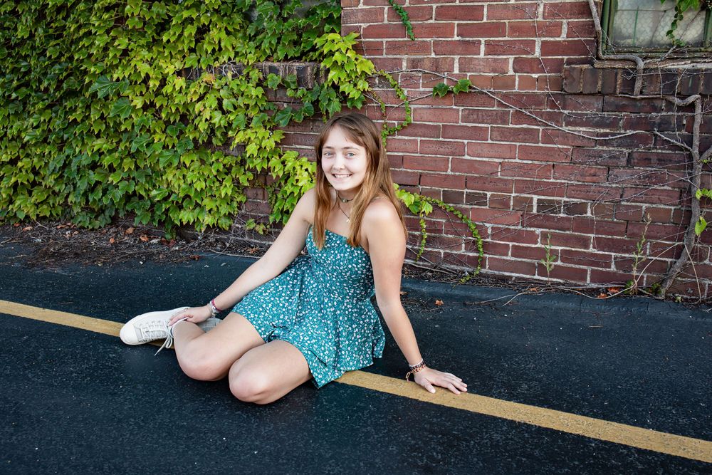 A turquoise summer dress against a brick wall backdrop with green ivy.