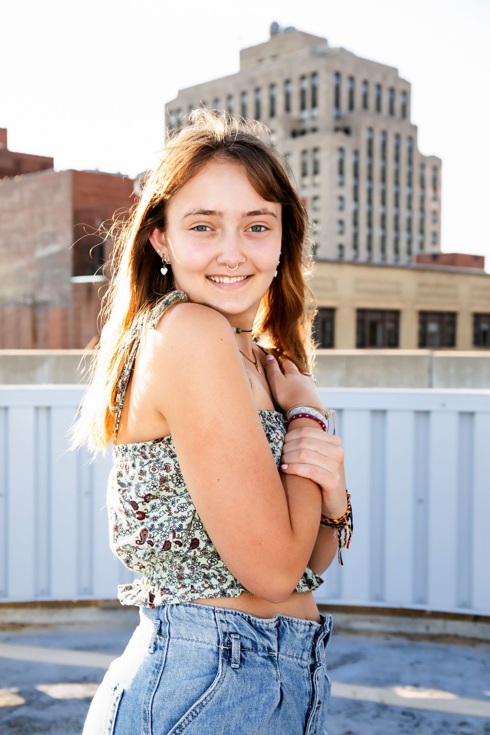 Rooftop fashion portrait with floral crop top and high-waisted jeans.