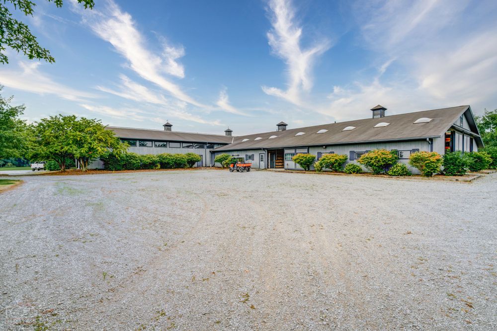 Long ranch-style building with gravel driveway and landscaped entrance under blue skies.