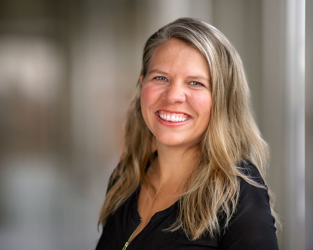blonde woman smiling for professional portrait in black shirt