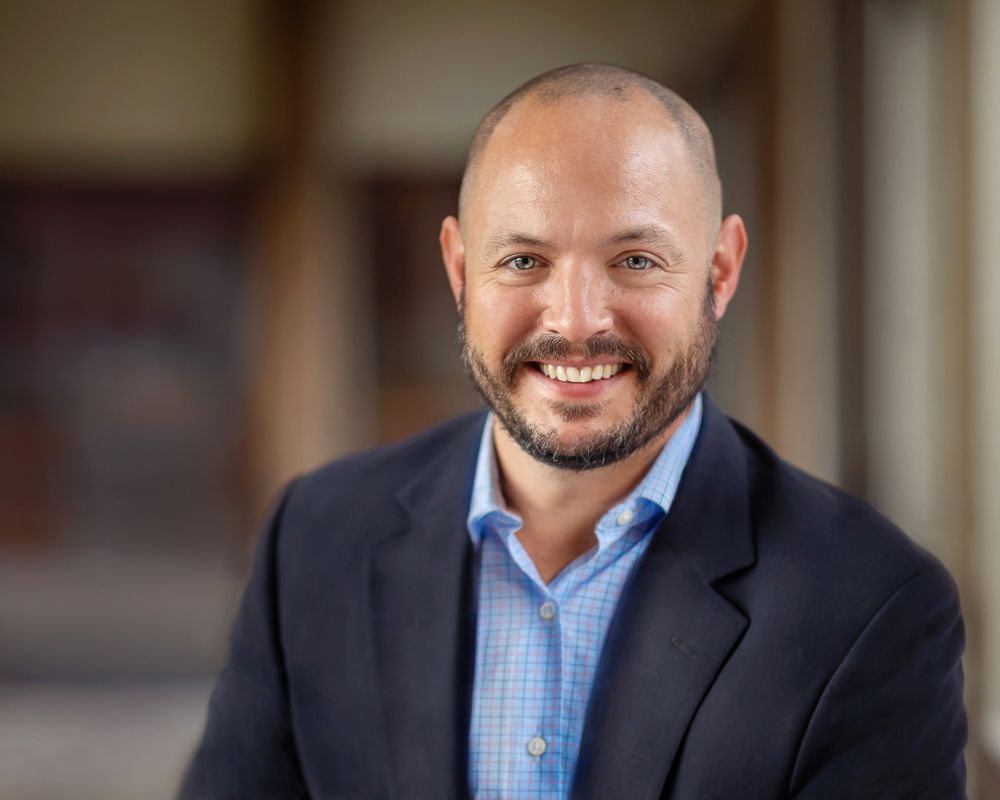 professional male in a blue shirt smiling for his business portrait