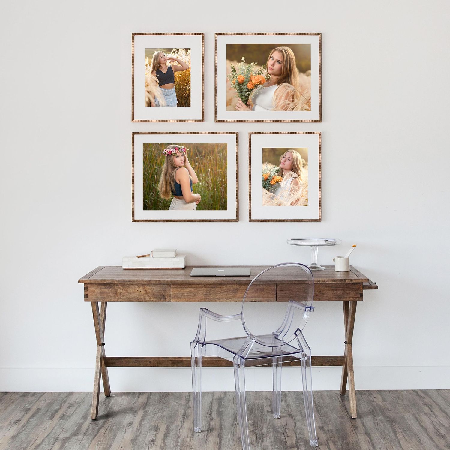 Gallery wall display with four framed portraits above a wooden desk with clear chair.