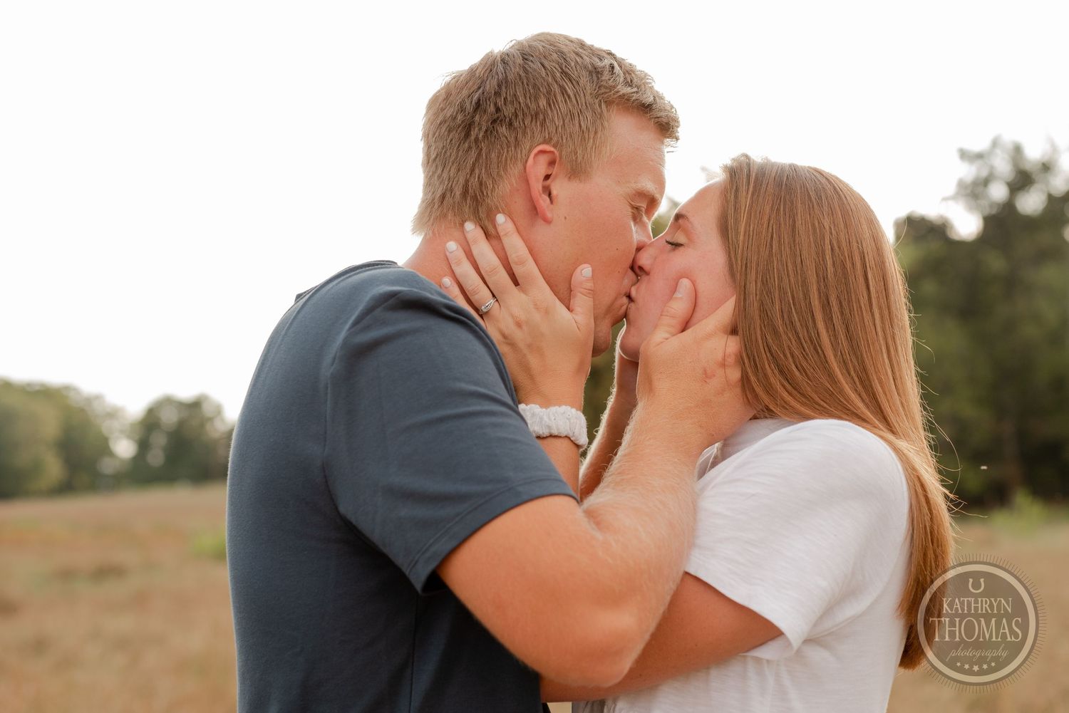 Intimate close-up of couple sharing romantic kiss in rural field setting.