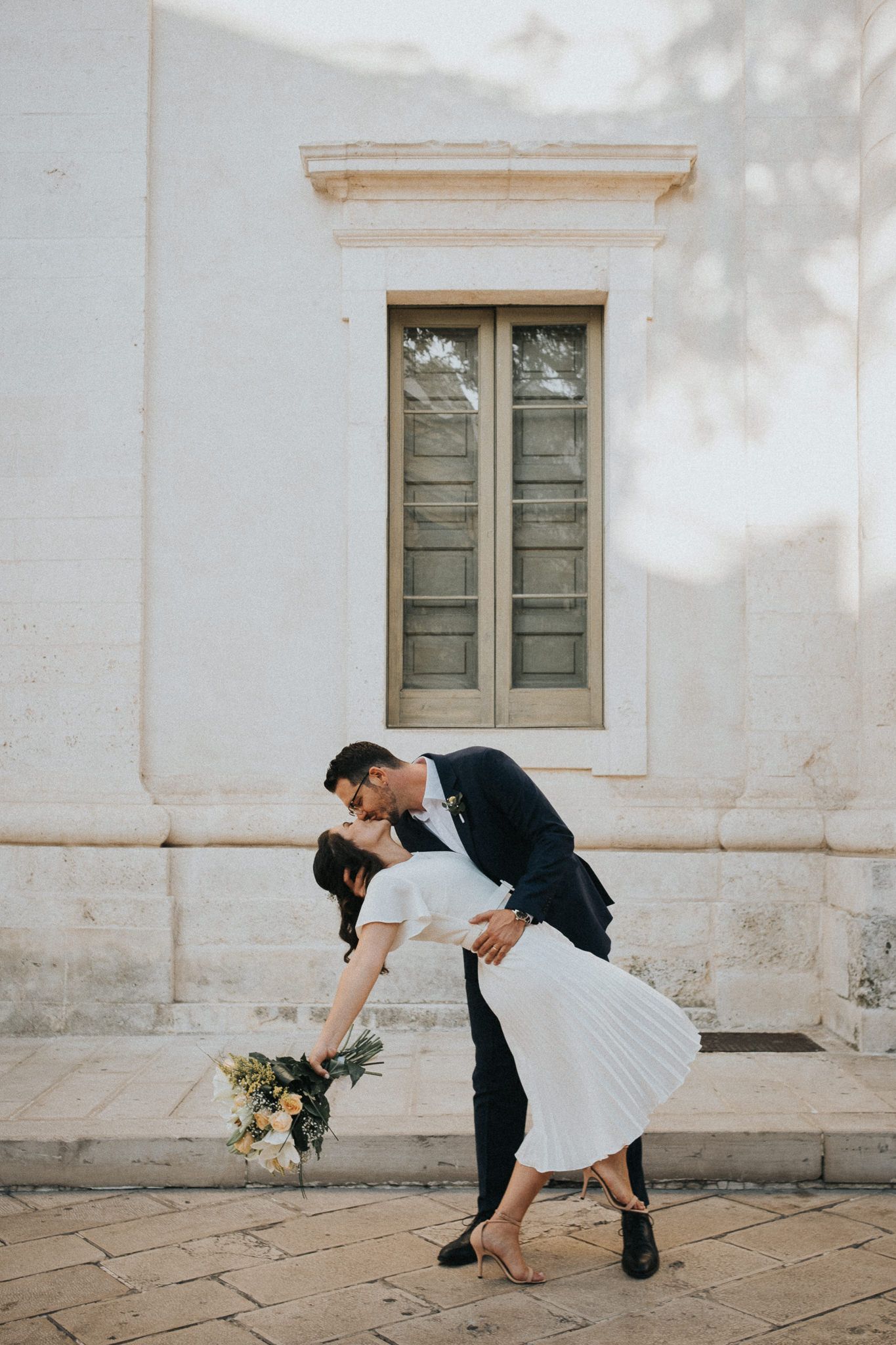 international wedding, couple kissing each other in Puglia  in front of the city hall