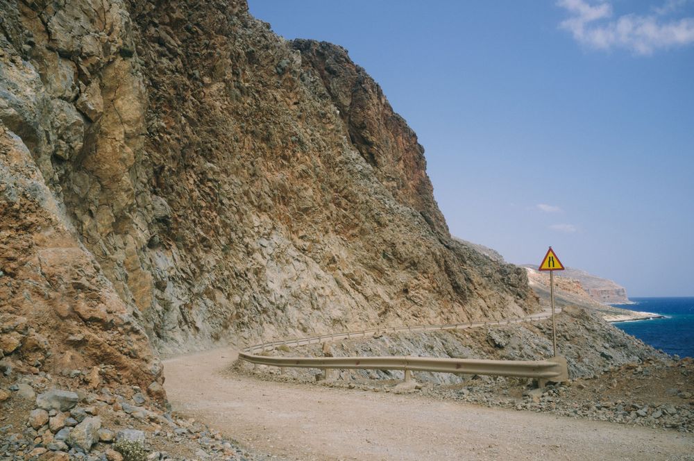 Winding coastal road carved into rocky cliffs overlooking the Mediterranean Sea.