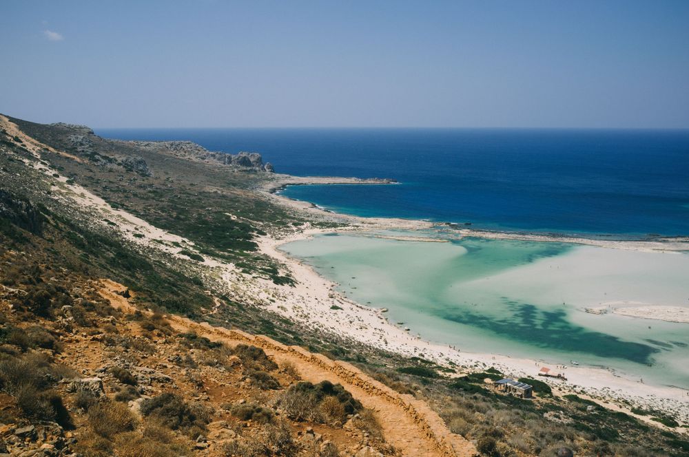 Aerial view of a curved coastline showing turquoise waters and sandy beaches.