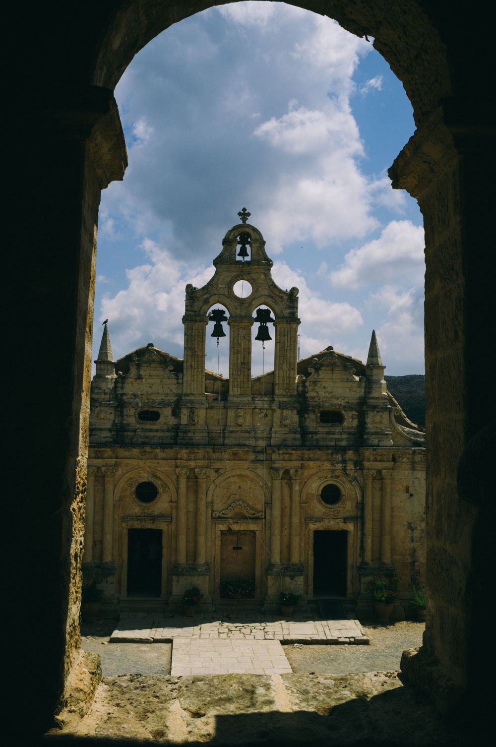 Ancient monastery viewed through stone archway with ornate architectural details.
