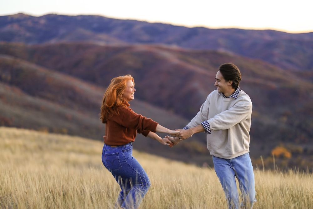 couple dancing in a field for their engagement photos.