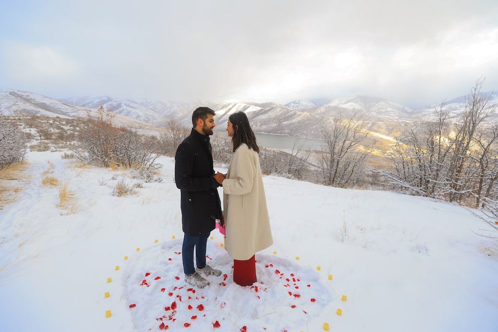 romantic proposal in Salt Lake City, couple holding flowers at sunset with snowy mountains.