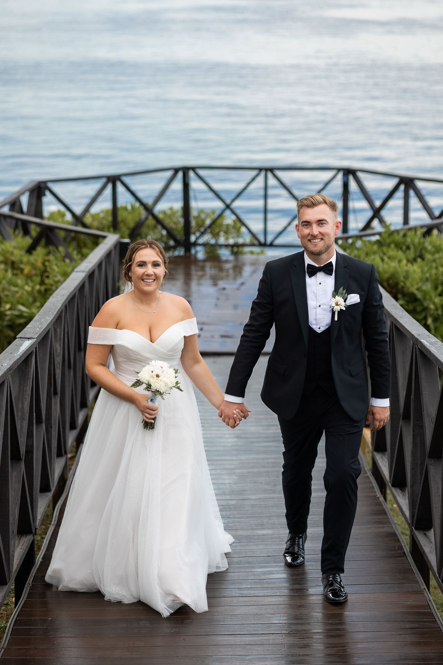 Bride and groom walking along pier in Jamaica
