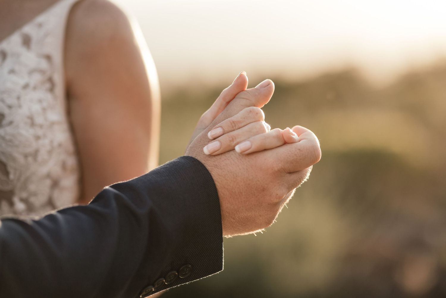 lose-up shot of bride and groom's interlocked hands, symbolising unity and love