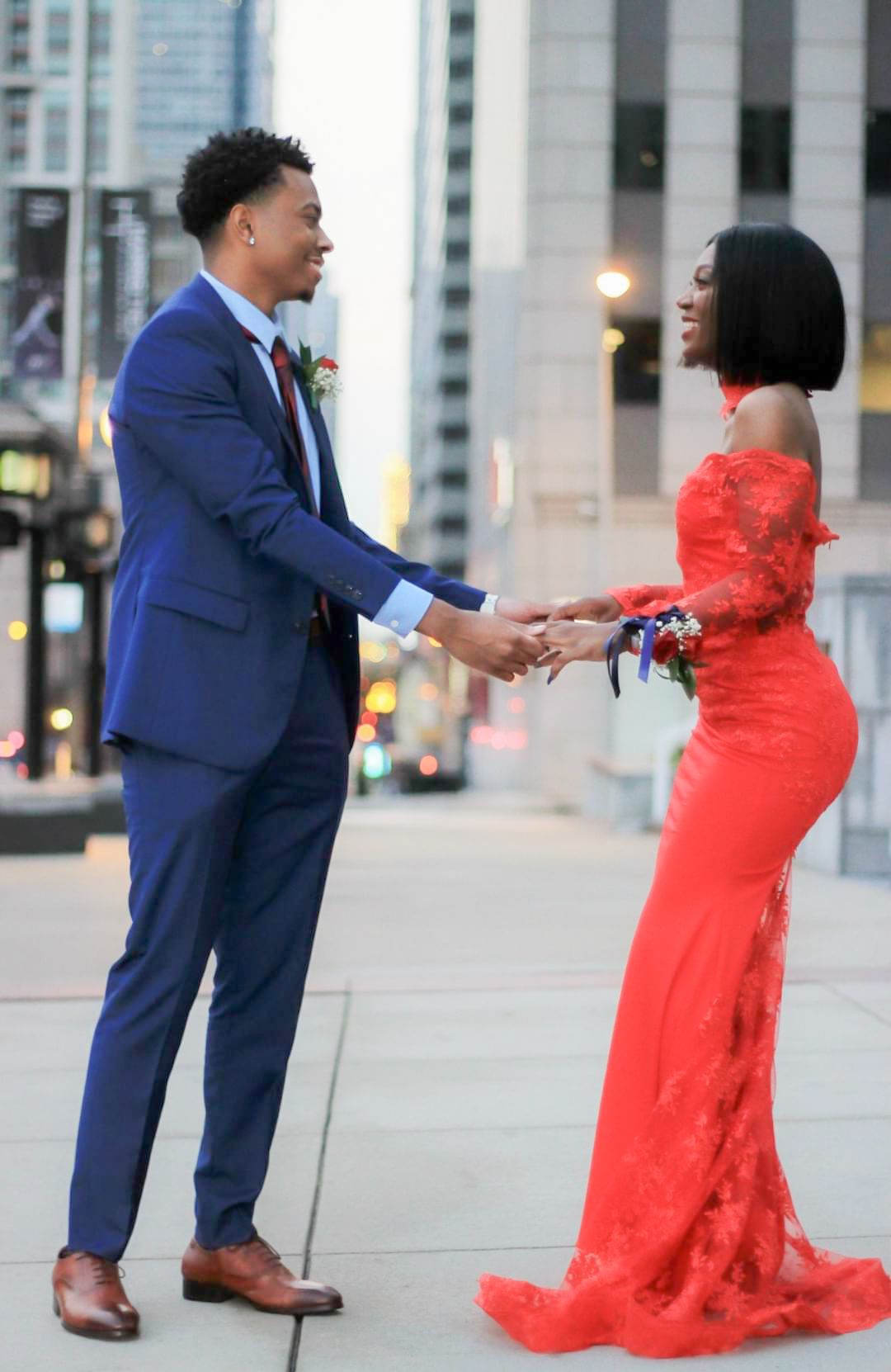 Picture of a couple holding hands on the sidewalk in a city.