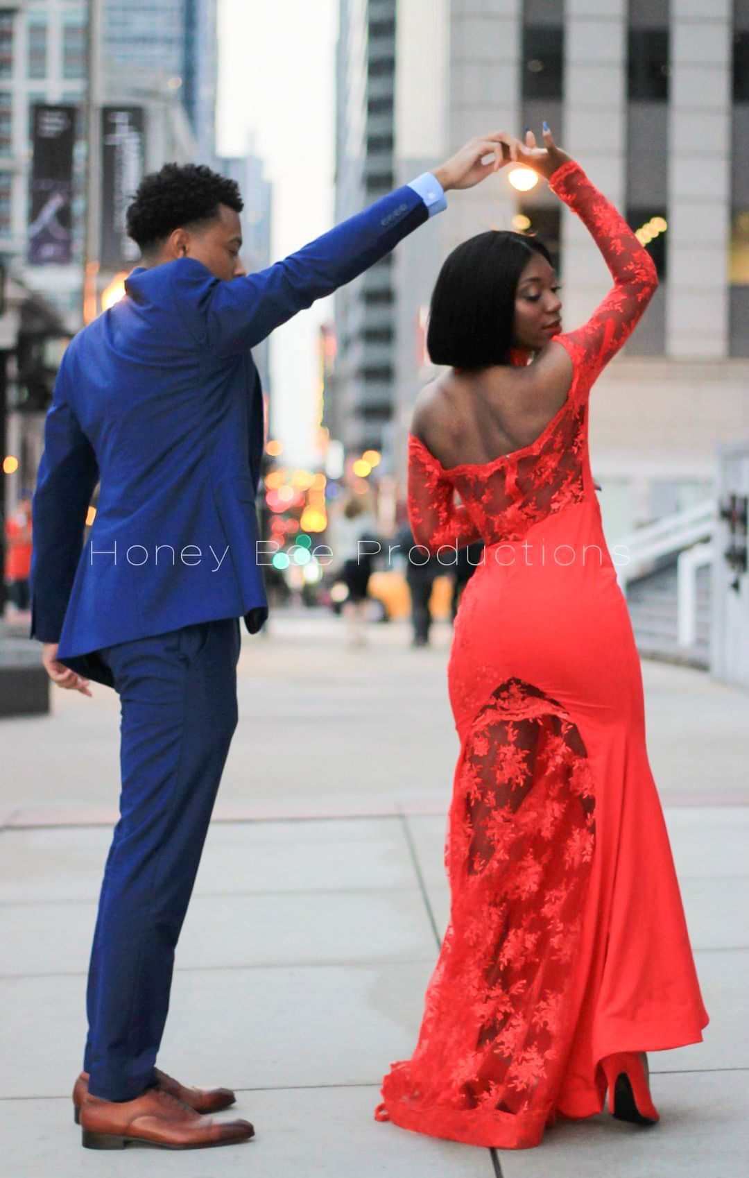 Picture of a couple dancing on the sidewalk in a city.
