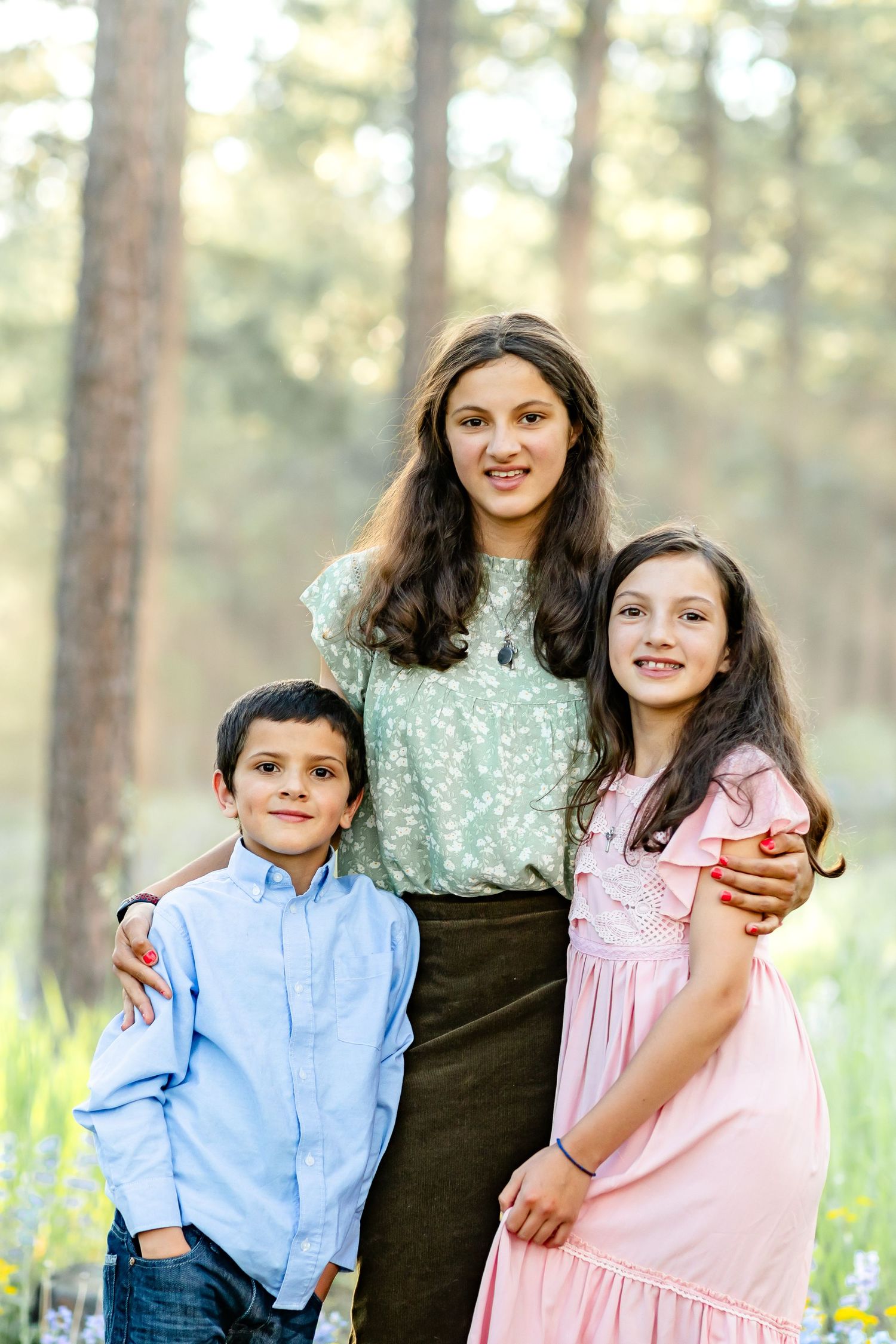 Three siblings pose together and smile during their family session in Colorado Springs.