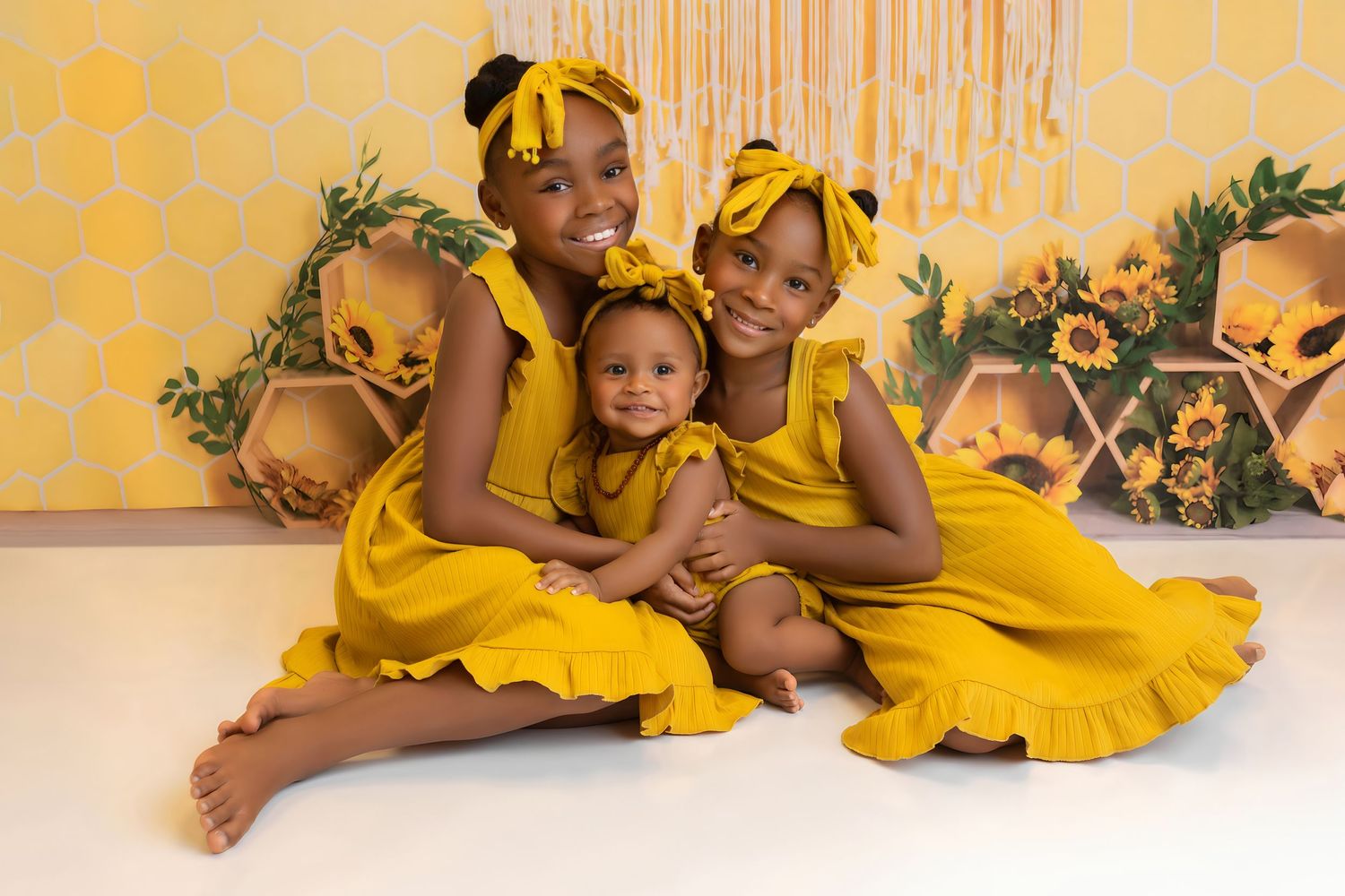 Children in matching yellow dresses pose with sunflowers and yellow decorations.