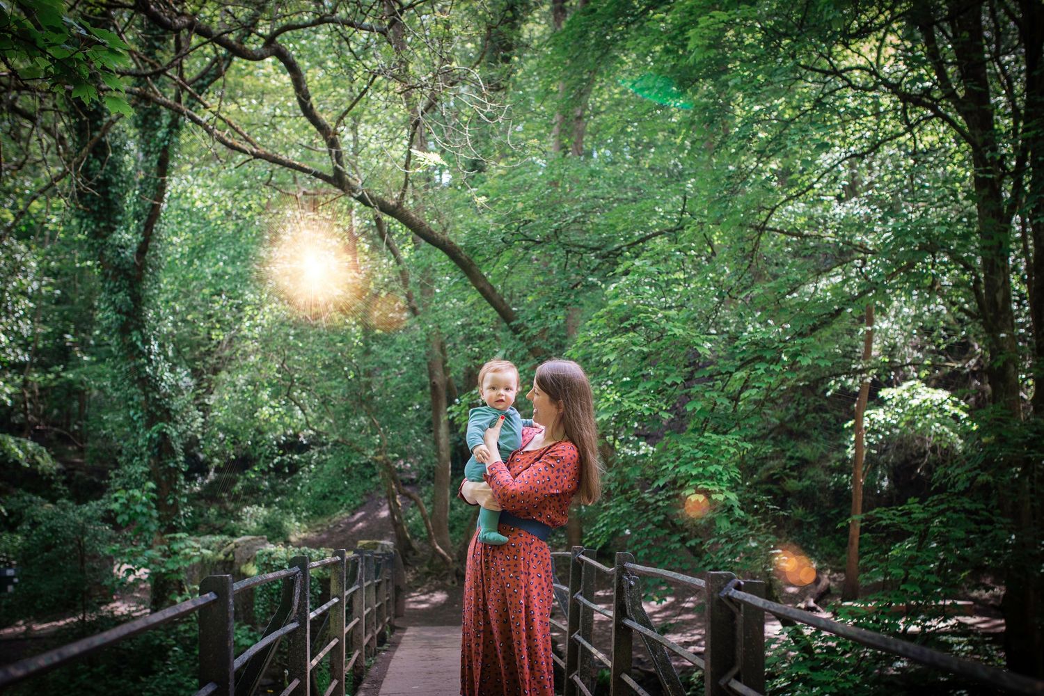 mother and baby standing on a bridge in a forest